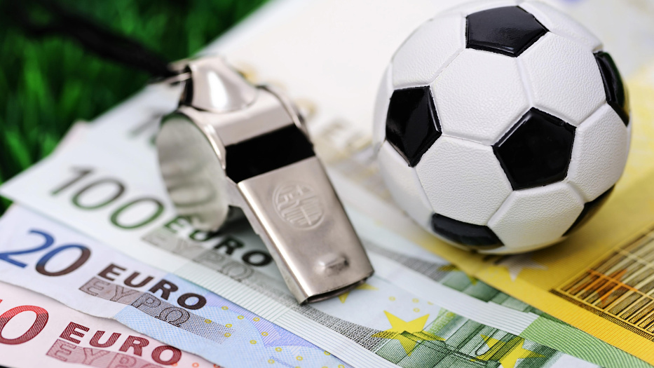 Ein kleiner Plastik-Fussball und eine Schiedsrichterpfeife liegen auf einem 500-Euro-Schein, darunter liegen weitere Scheine im Wert von 100, 20 und 10 Euro.  